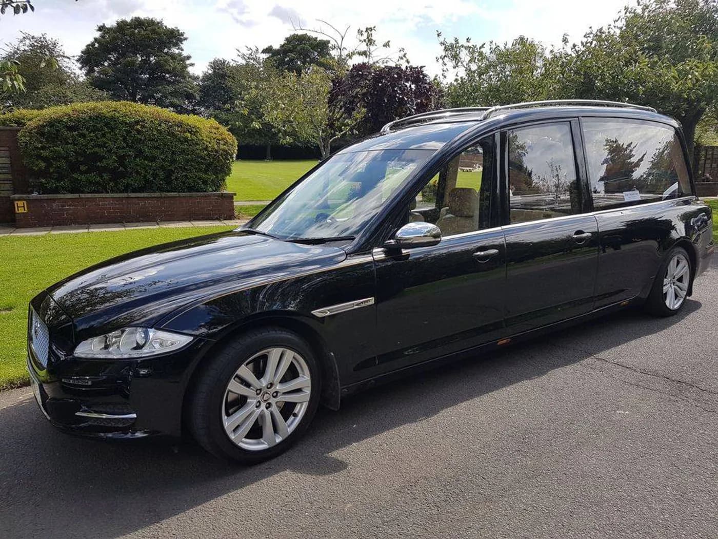 The Jaguar hearse parked on a road beside a lawn